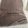 Acne Studios crossed-strap baseball cap in brown, close detail of logo strap