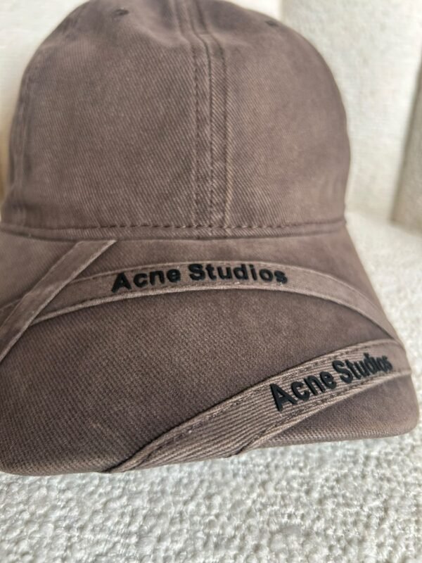 Acne Studios crossed-strap baseball cap in brown, close detail of logo strap