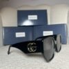 Black oversized geometric sunglasses, angled view showing the wide gold logo temple