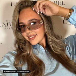 Model wearing Miu Miu MUA51S rimless sunglasses in grey and gold with a light blue windbreaker
